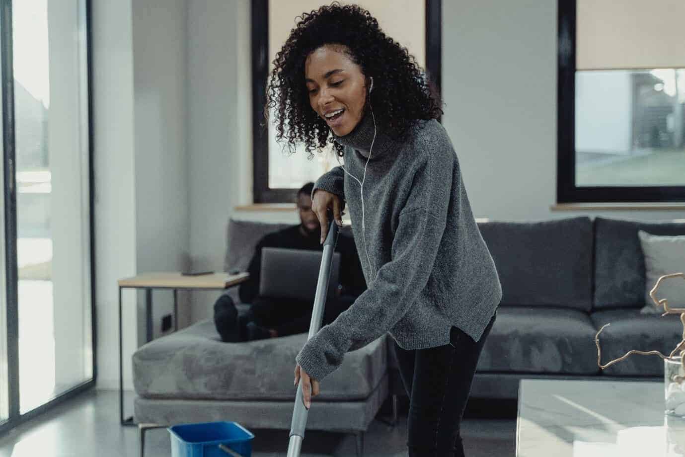 Woman smiling whilst mopping the floor